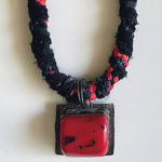 Fiber and beaded necklace with red pendant.