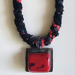 Fiber and beaded necklace with red pendant.
